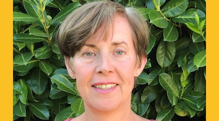 Image shows Caroline looking at camera with leaves background