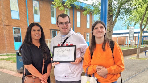 Image shows Anita, Mathew and Lisa standing outside Cranford Community College and Michael is holding the Award Certificate. Everyone is smiling.