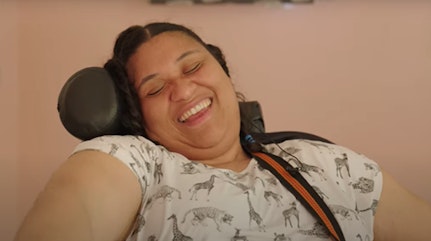 Image shows Rachel smiling whilst playing her guitar