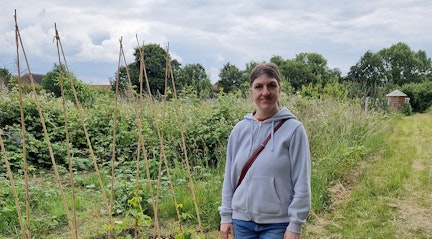 Images shows Lisa stood amongst the Blooming Marvellous community allotment with lots of produce growing around her