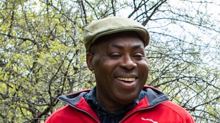 Image shows Promise smiling with trees in the background