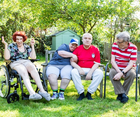 image shows a diverse group of people laughing in the garden